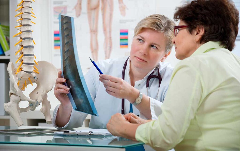 Person gently touching the jaw while seated upright with visible neck and shoulder tension.