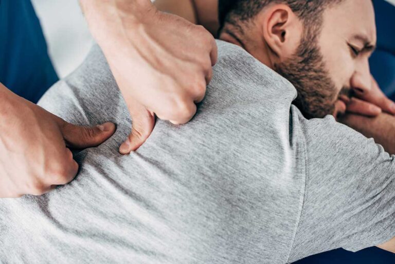 Person seated safely while a clinician evaluates head position and balance during a vertigo assessment.