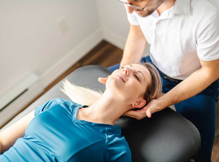 A chiropractor checking a middle-aged person’s posture while discussing movement and flexibility in a bright clinic setting.
